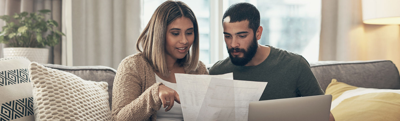 A couple looking at their energy bills on a couch in a living room.