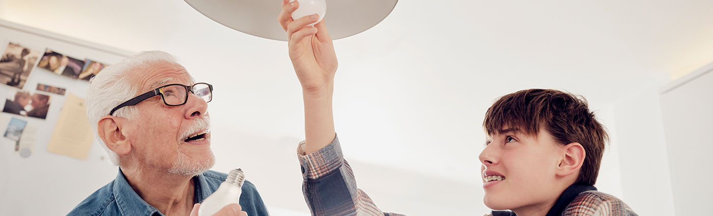 A grandfather watching his grandson change the light bulb.